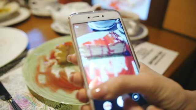 Woman taking picture of cheesecake By Smartphone.