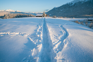Deep snow trail paths in sunlit alpine winter landscape in Wildermieming, Tirol, Austria