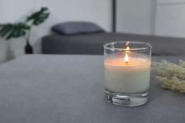 Obraz na płótnie Canvas glass of aroma scented candle is on the grey table in the white bedroom with background of grey ped and pillow in the morning of valentine day