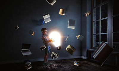 Boy holding a light bulb with books around him