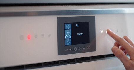 Close up of woman pushing buttons on touch panel of microwave or oven.