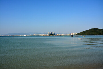 calm sea horizon with city buildings far away under blue sky