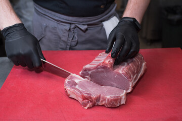Cutting pork meat. Chef working in the kitchen in a pub