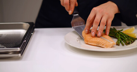 Chef serving dish salmon steak fillet and garnished with wild asparagus