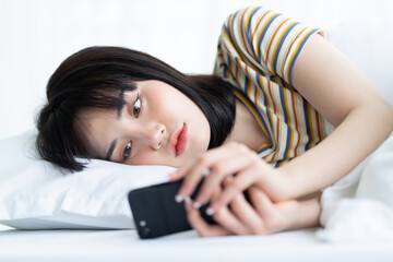 Obraz na płótnie Canvas Beautiful Asian woman using phone on bed in bedroom