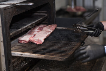 A chef in a very nice pub smokes pork ribs in a large oven
