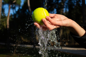 hand throws the tennis ball  with water splashing around it. Water splash with sport ball