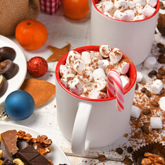 sweet food top view background for merry christmas or new year holiday decoration - chocolate candies, tangerines, cookies, marshmallow and cocoa latte on white wood