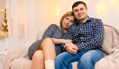 portrait of adult couple sitting on a sofa at home