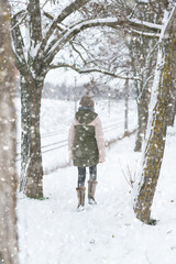 Fototapeta na wymiar teen girl walks on a snow-covered path in winter, a teenage boy and a girl, a snowstorm