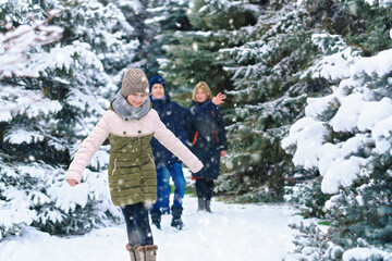 Fototapeta na wymiar family walking in the winter forest, two parents and two children, beautiful nature with bright snowy fir trees