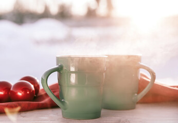 Vintage rustic card with green porcelain cups of tea on white wooden table decorated with red Christmas balls. Winter seasonal holiday background. Food and drink concept. Closeup.