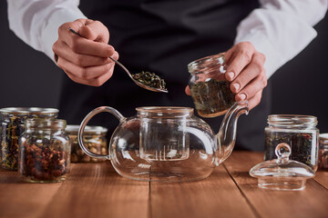 Tea master pouring green tea leaves into a glass pot