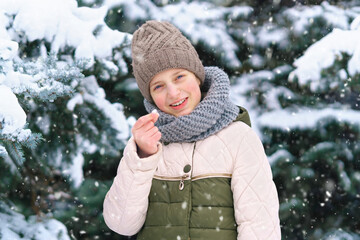 child girl playing with snow in the winter forest, bright snowy fir trees, beautiful nature