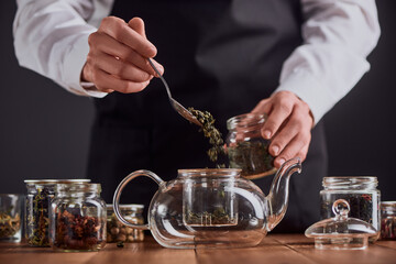 Barista putting green tea leaves into a teapot
