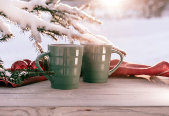 Vintage rustic card with green porcelain cups of tea on white wooden table decorated with snowy fir tree and red Christmas balls. Winter seasonal holiday background. Food and drink concept.