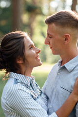 Cheerful young woman and man are hugging outdoors in summer park. Dating and romantic vacation. couple in love gently looking at each other on sunny day. Love and relationships between young people