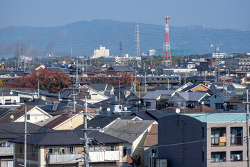 Fototapeta na wymiar 南大阪の市街地を走る電車風景と奥に見える信貴山と生駒山
