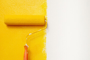Roller Brush Painting, Worker painting on surface wall  Painting apartment, renovating with yellow color  paint. Leave empty copy space white to write descriptive text beside.
