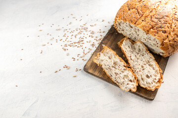 Sliced bread on serving board with flax and sunflower seeds. Fresh, tasty, round wheat bread with...