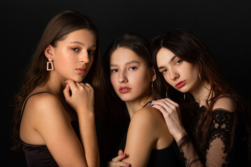 Obraz premium three beautiful young women with makeup and hairstyle on a black background 