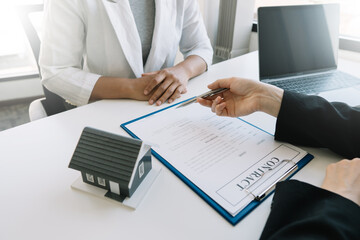 Buying a home or insurance deal, an insurance agent pointing a pen to those interested in renting a house, signing a contract, signing an agreement.