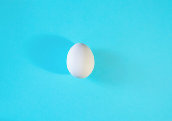 Easter concept. One white egg isolated on color blue pastel background.