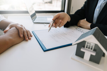 Buying a home or insurance deal, an insurance agent pointing a pen to those interested in renting a house, signing a contract, signing an agreement.