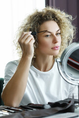 Young beautiful woman is using eyebrow tinting brush