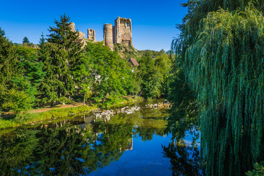 the ruins of the medieval castle of Herisson reflecting the peaceful Aumance river in Auvergne (France)