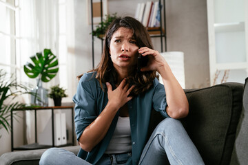 Happy young woman talking to the phone at home. Excited woman enjoying in the living room.