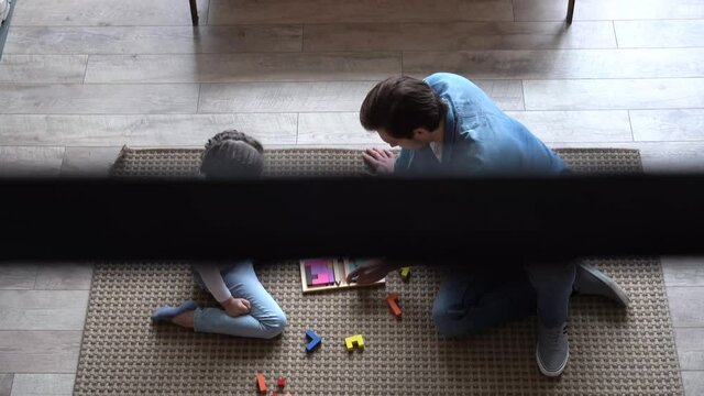 Happy parent dad helping daughter playing toys together on floor, having fun