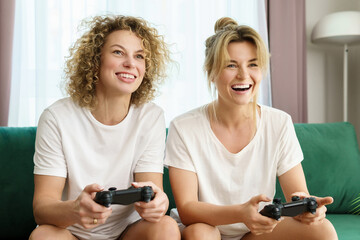 Two beautiful girls playing video game console in  living room