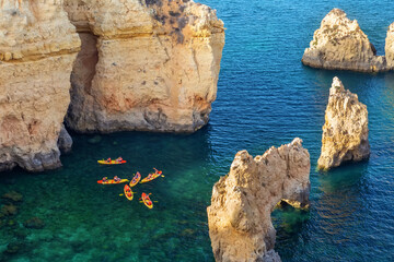 Aerial view of rocky coast in Ponta da Piedade in Lagos, with kayak group in clear ocean water....