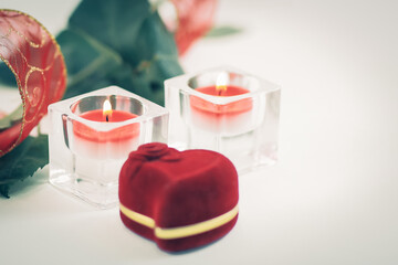 box with ring, rose and two candles on white background