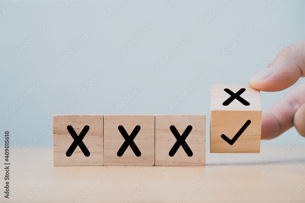 Poster Hand flipping wooden cube block to change cross incorrect to correct mark.