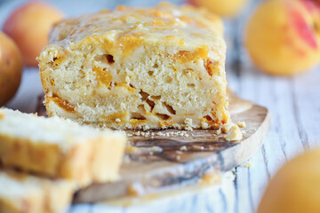 Delicious homemade peach sweet bread with frosting and fresh peaches. Selective focus with blurred foreground and background. 