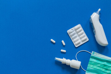 FFP3 mask, nasal drops, thermometer, tablets, various medicines lie on the table, top view, on a...