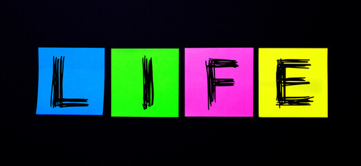 On a black background, bright multicolored stickers with the word LIFE. Illustration