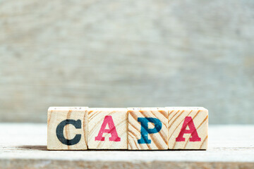 Alphabet letter block in word CAPA (abbreviation of corrective action and preventive action) on wood background