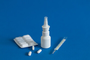 FFP3 mask, nasal drops, thermometer, tablets, various medicines lie on the table, top view, on a blue background