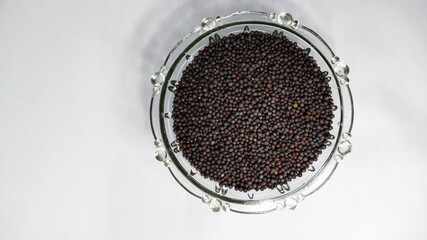 mustard seeds in glass bowl on a white isolated surface