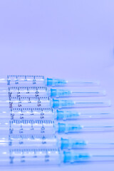 Close-up of group of syringes laid out in row one after another on table. Empty syringes in row on light blue background. Vaccination covid-19. The course of patient's treatment. Selective focus