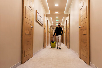 Man with travel bag walking through a hallway.