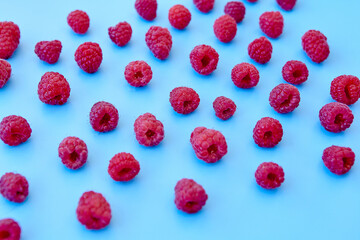 Raspberry pattern, blue background, top view.Pattern of ripe red raspberry on blue background. Vegan food, detox concept