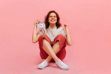 Obraz na płótnie Canvas Studio shot of excited girl with clock isolated on pink background. Blissful lady showing time.