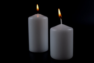 Białe, grube świeczki na ciemnym tle.