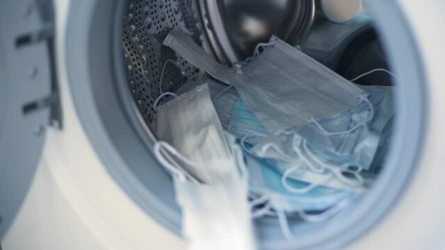 Woman puts surgical mask into washing machine Sustainable consumption