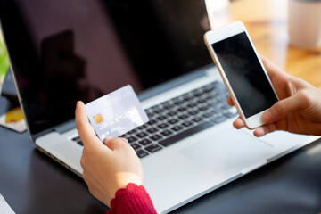 Close up woman hand using credit card and smartphone laptop for buying online shopping