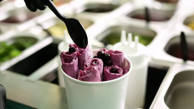 Stir-fried ice cream rolls at freeze pan. Rolled ice cream, hand made ice cream dessert. Fried ice cream machine with steel chilled pan.